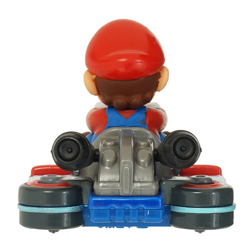 Toy figure of a character in a red hat and blue overalls sitting in a toy car on a white background